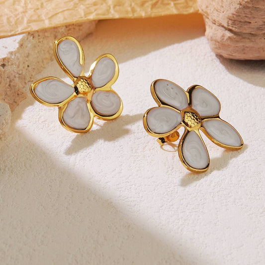 Flower-shaped earrings with gold and white design on a textured surface Orlaya Jewellery