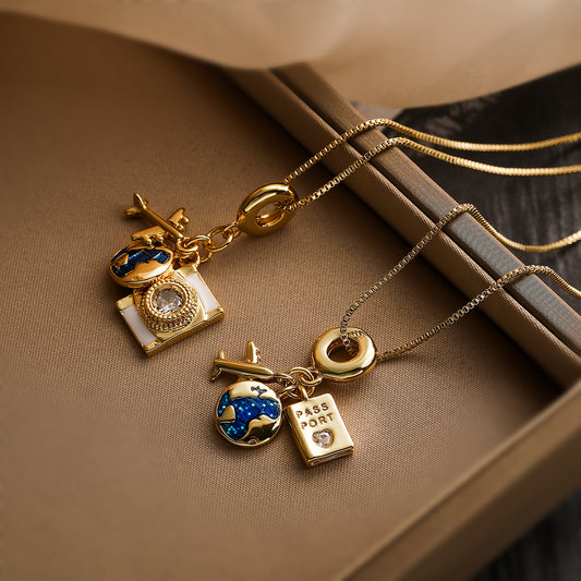 Gold travel necklace with globe and camera charms — wanderlust jewellery