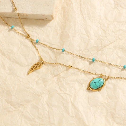 Layered gold necklace with turquoise stone and wing pendant