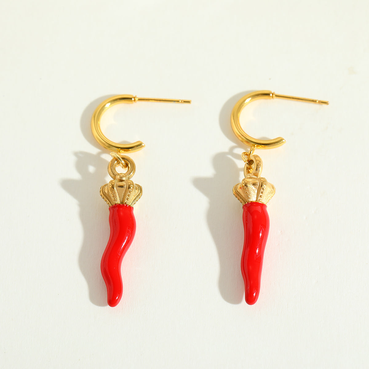 Calabria Charm gold earrings with red chilli charms flat lay