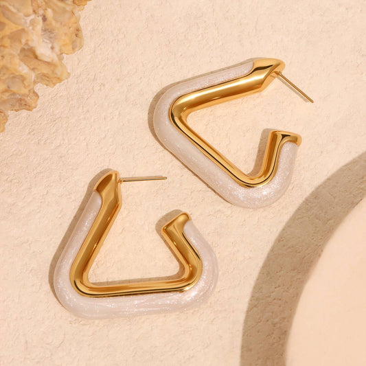 Gold and white hoop earrings on a beige background Orlaya Jewellery