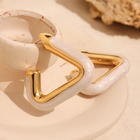 Close-up of Nova Edge 18K gold-plated geometric hoop earring with pearly white detail on beige background – Orlaya Jewellery.