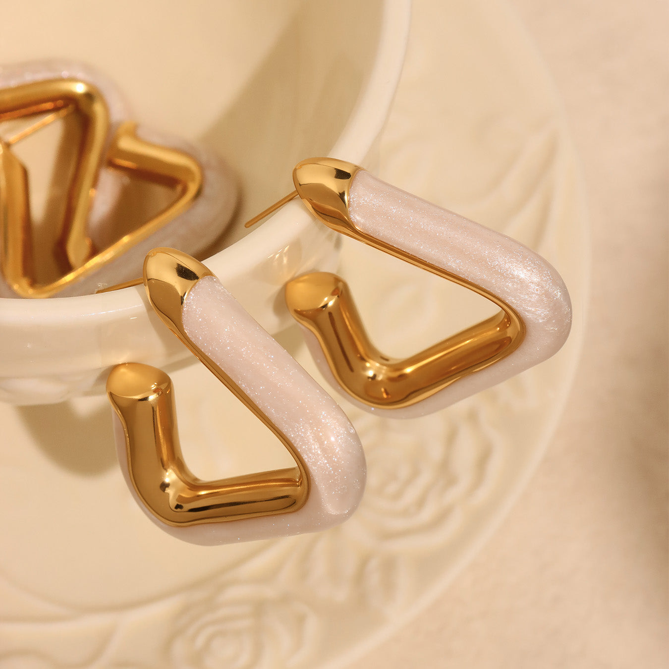 Side view of Nova Edge 18K gold-plated geometric hoop earrings with pearly white detail in a ceramic dish – Orlaya Jewellery