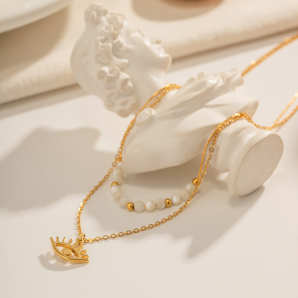Close-up of gold evil eye pendant on a delicate chain — cult talisman jewelry
