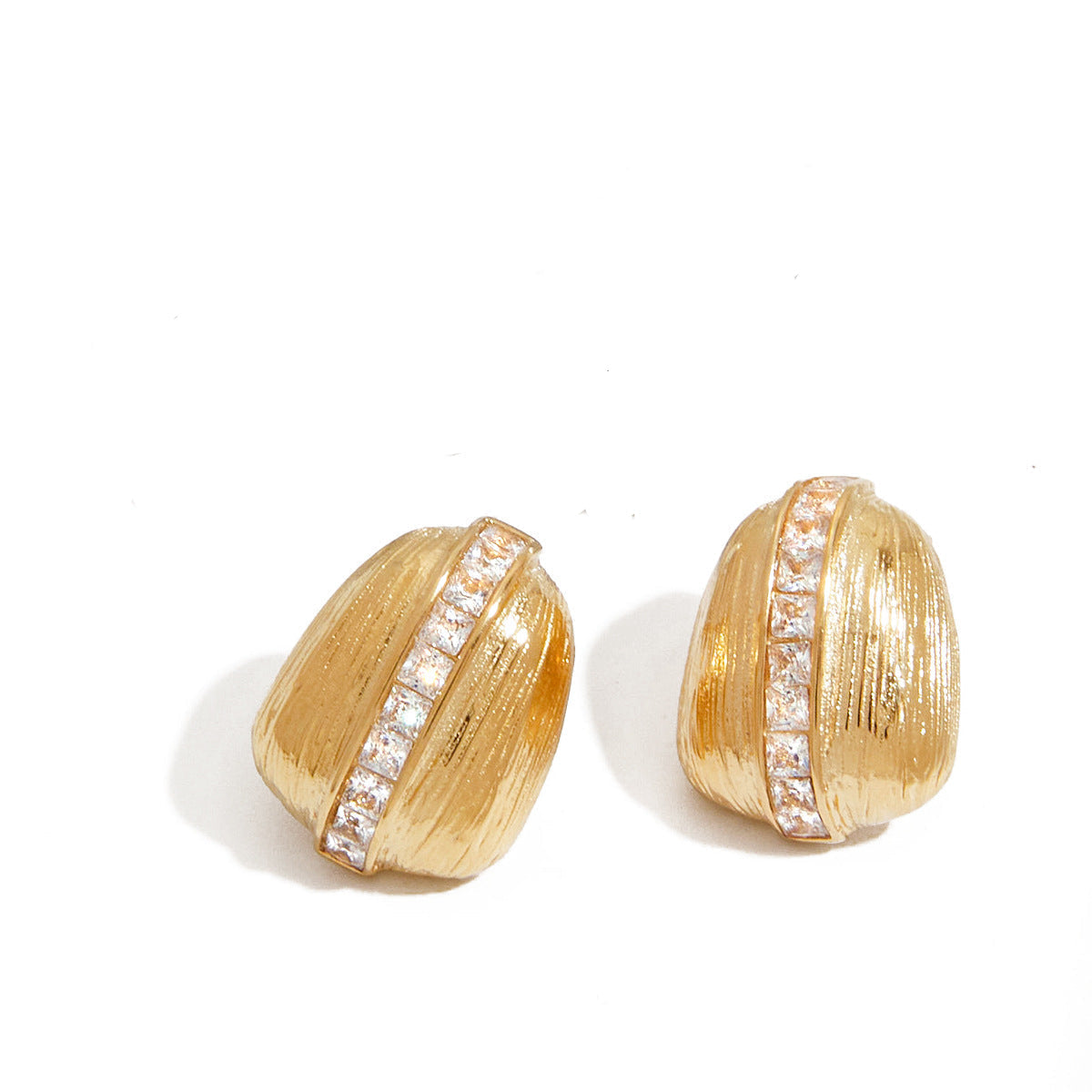 Vintage-inspired gold stud earrings with soft ridges and a central crystal accent on a white background